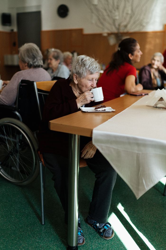 hero-about Elderly group enjoying tea and cake in a senior community center in Karviná.