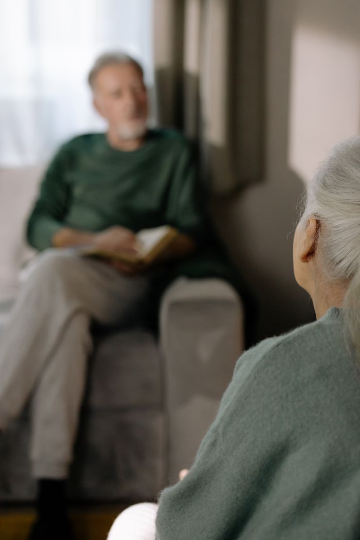 about-02 A serene moment between senior adults sitting together indoors, embracing companionship.