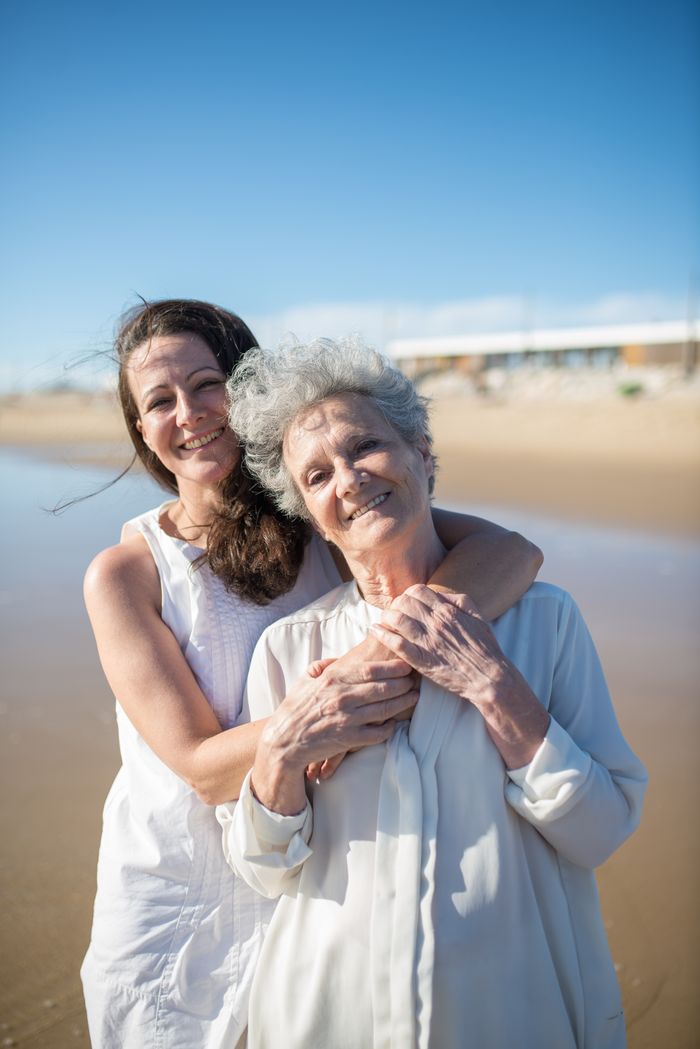 A joyful moment of mother and daughter hugging on a sunny beach in Portugal.